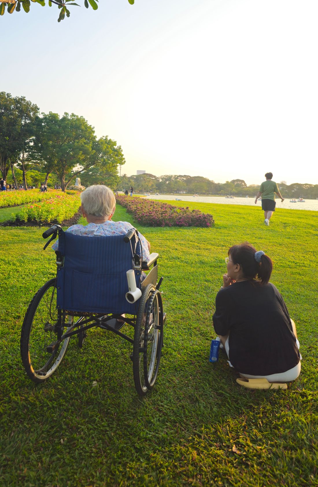 A caregiver crouching beside an older person in a wheelchair, talking with them.